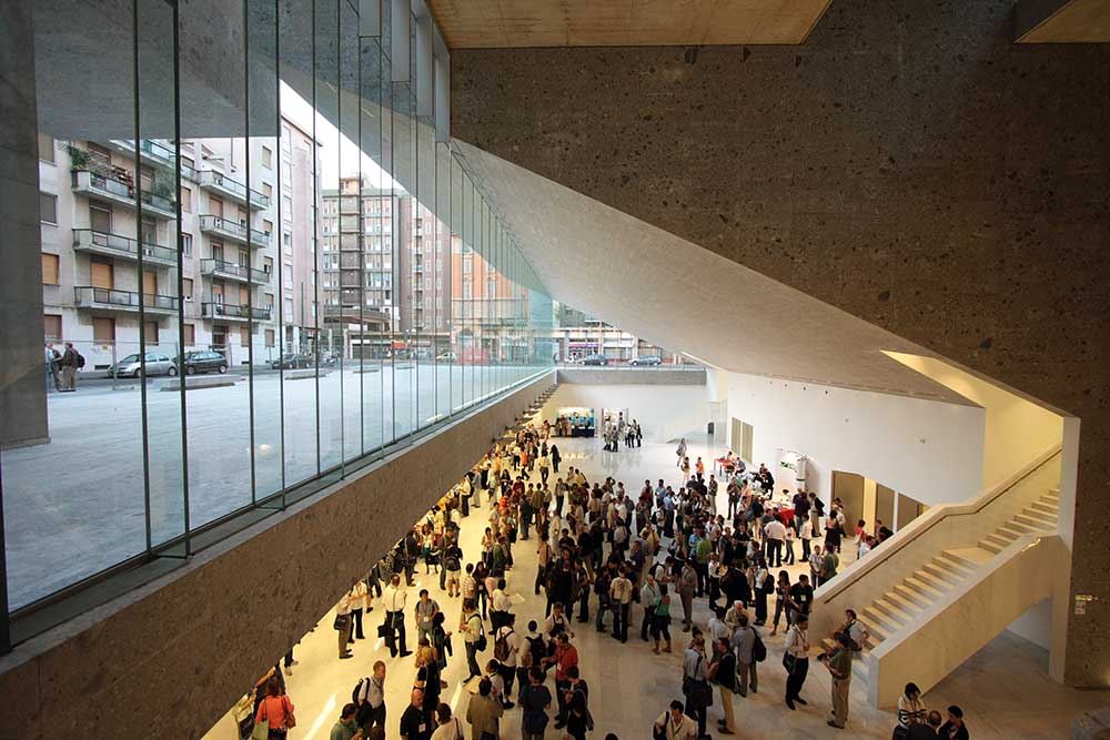 Indvendig udsigt af Universita Luigi Bocconi-bygningen med en mængde mennesker og vinduer, der viser gaden.