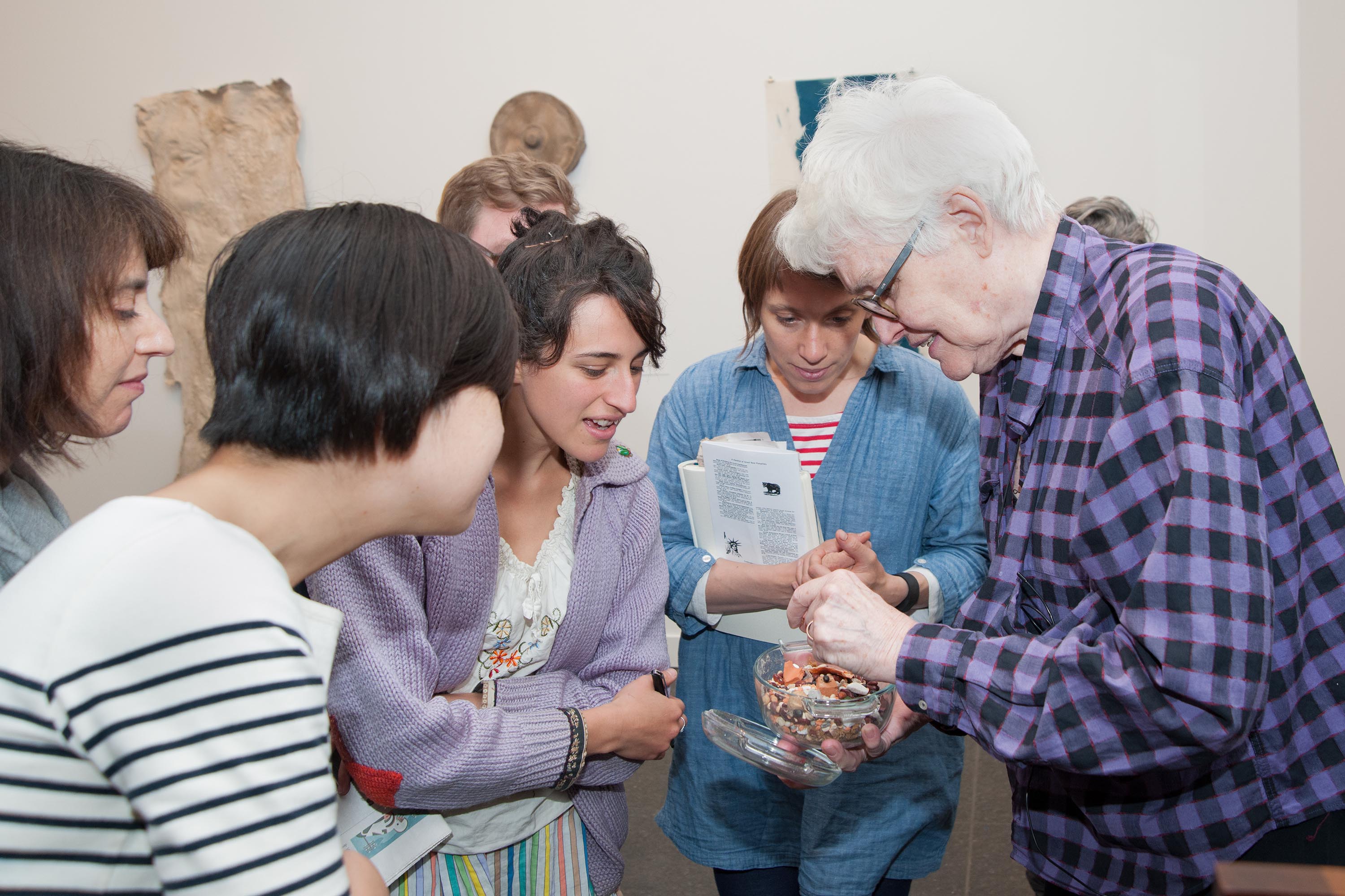 Alison Knowles samler kunstnergruppen for at undersøge små artefakter fra hendes krukke.